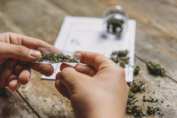 close-up photo of the hands of a young man rolling a joint
